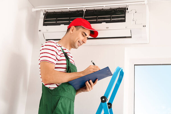 Male technician repairing air conditioner indoors