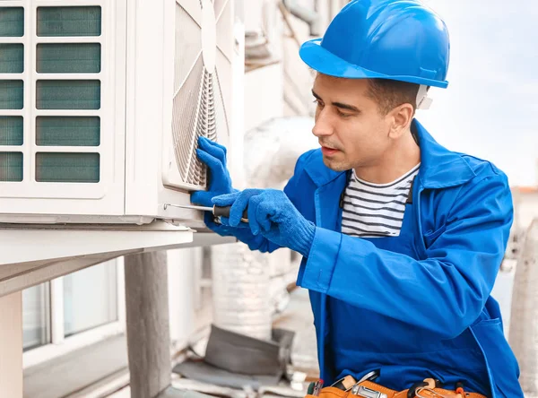 Técnico masculino instalando unidade ao ar livre de ar condicionado — Fotografia de Stock