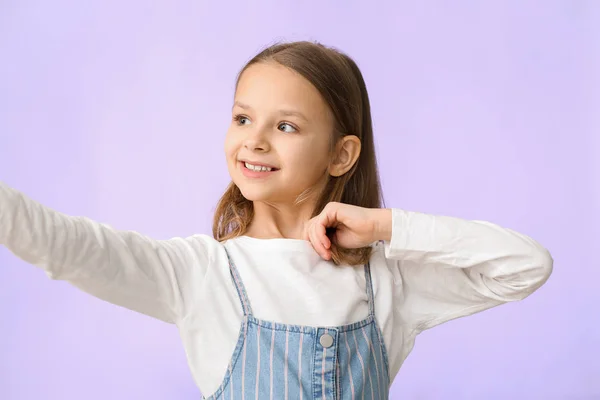 Милая маленькая девочка делает селфи на цветном фоне — стоковое фото