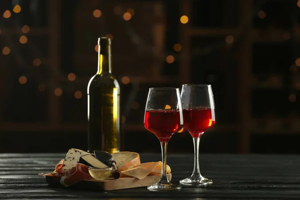 Очки и бутылка вкусного вина с закусками на столе в баре — стоковое фото