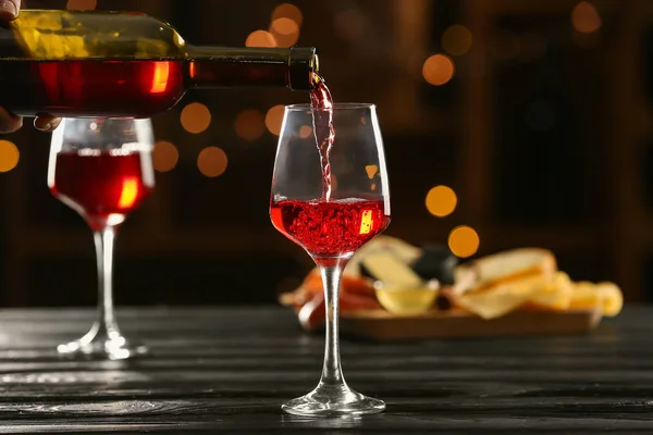 Наливание вкусного вина из бутылки в бокал на стол в баре — стоковое фото