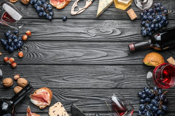 Moldura feita de vinho delicioso com lanches em fundo de madeira escura — Fotografia de Stock