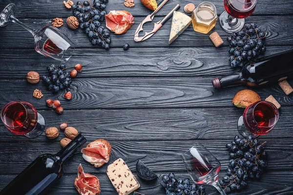 Moldura feita de vinho delicioso com lanches em fundo de madeira escura — Fotografia de Stock