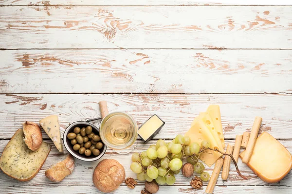 Delicioso vinho com lanches em fundo de madeira branca — Fotografia de Stock