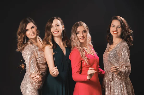 Beautiful young women with Christmas sparklers on dark background — Stock Photo, Image