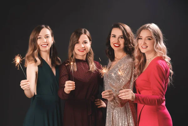Krásné mladé ženy s vánoční jiskry na tmavém pozadí — Stock fotografie