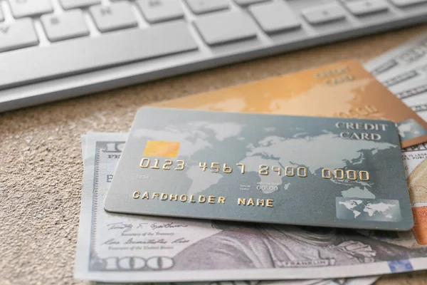 Кредитні картки з грошима та комп'ютерною клавіатурою на сірому фоні, крупним планом. Концепція онлайн банкінгу — стокове фото