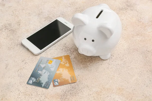 Credit cards with piggy bank and mobile phone on grey background. Concept of online banking — Stok fotoğraf