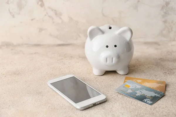 Credit cards with piggy bank and mobile phone on grey background. Concept of online banking — Stok fotoğraf