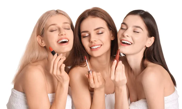 Hermosas mujeres jóvenes aplicando maquillaje sobre fondo blanco — Foto de Stock
