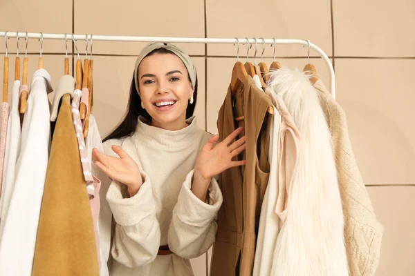 Female stylist near rack with modern clothes