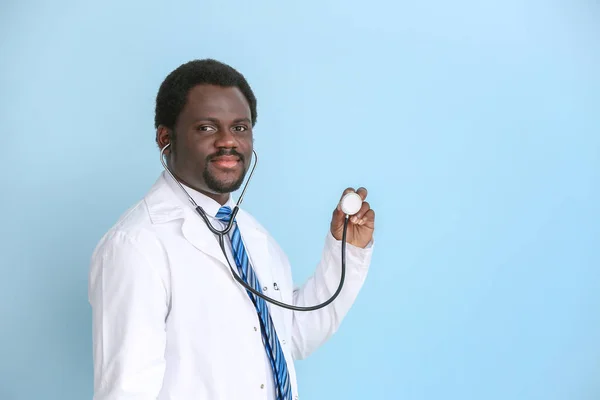 African-American doctor with stethoscope on color background — Stock Photo, Image