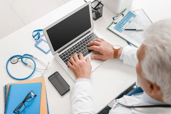 Médico masculino com laptop sentado à mesa na clínica — Fotografia de Stock