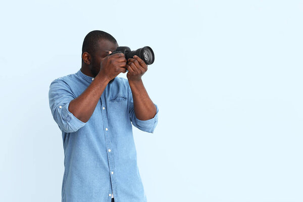 African-American photographer on color background