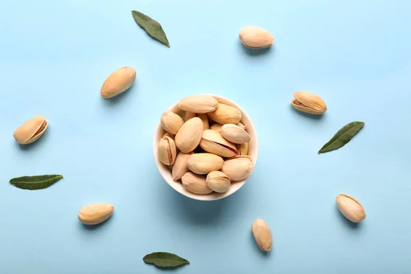 Bowl with tasty pistachio nuts on color background — Stock Photo, Image