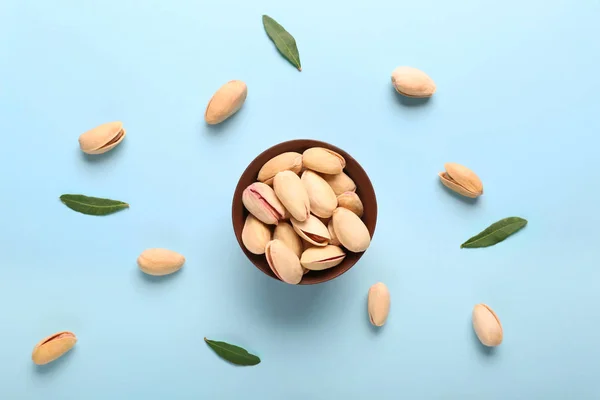 Bowl with tasty pistachio nuts on color background — Stock Photo, Image