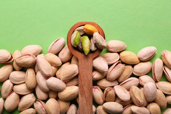 Spoon and tasty pistachio nuts on color background — Stock Photo, Image