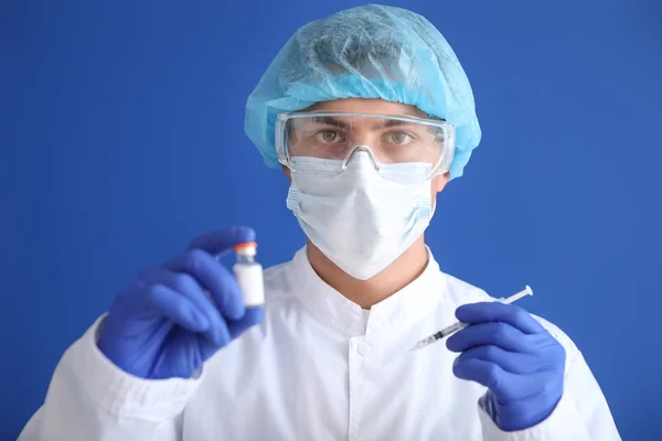 Labormitarbeiter in Schutzuniform und mit Impfstoff auf farbigem Hintergrund. Konzept der Epidemie — Stockfoto