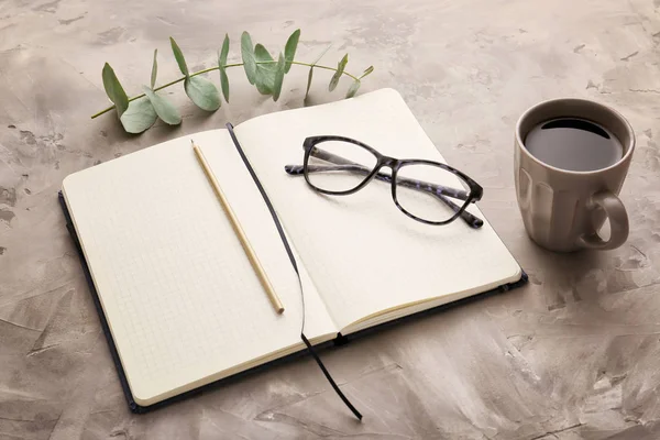 Notebook with cup of coffee, eyeglasses and pencils on grunge background — Stock Photo, Image