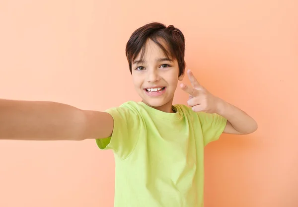 Cute little boy taking selfie on color background Stock Photo