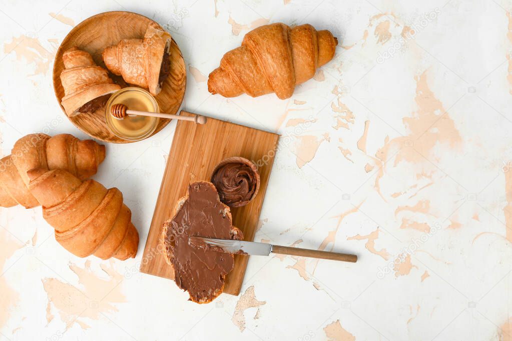 Tasty sweet croissants with chocolate and honey on white background