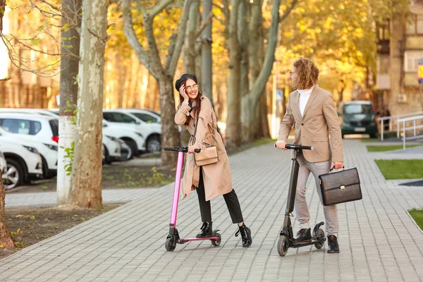 Young couple riding kick scooters outdoors — Stock Photo, Image