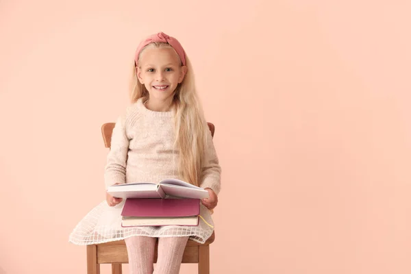 Little girl reading book on color background — Stok fotoğraf