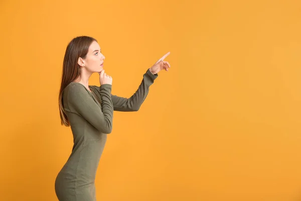 Young woman pointing at something on color background. Concept of choice — Stock Photo, Image