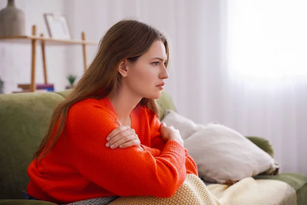 Deprimida jovem mulher sentada no sofá em casa — Fotografia de Stock