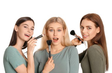 Beautiful young women applying makeup on white background