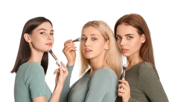 Mooie jonge vrouwen toepassen van make-up op witte achtergrond — Stockfoto