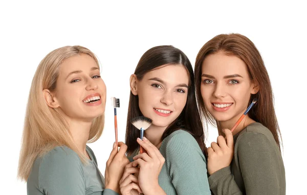 Hermosas mujeres jóvenes aplicando maquillaje sobre fondo blanco — Foto de Stock