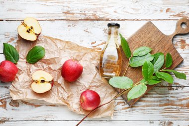 Beyaz ahşap arka planda bir şişe elma sirkesi.
