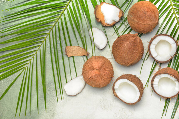 Спелые кокосы и пальмовые листья на светлом фоне
