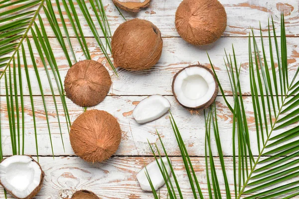 Cocos maduros e folhas de palma sobre fundo de madeira — Fotografia de Stock