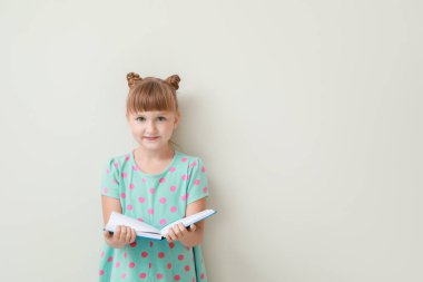 Işıklı arka plan kitabı olan sevimli küçük bir kız.