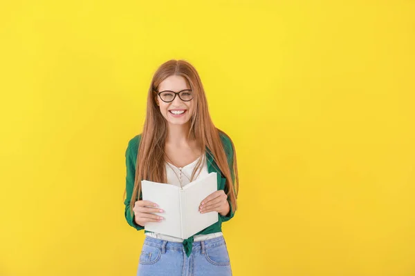 Schöne junge Frau mit Buch auf farbigem Hintergrund — Stockfoto