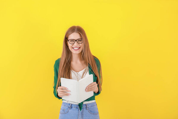 Beautiful young woman with book on color background