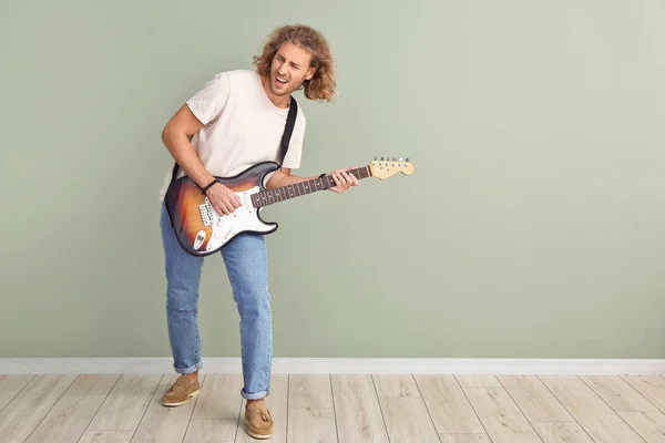 Hombre tocando la guitarra contra la pared de color — Foto de Stock