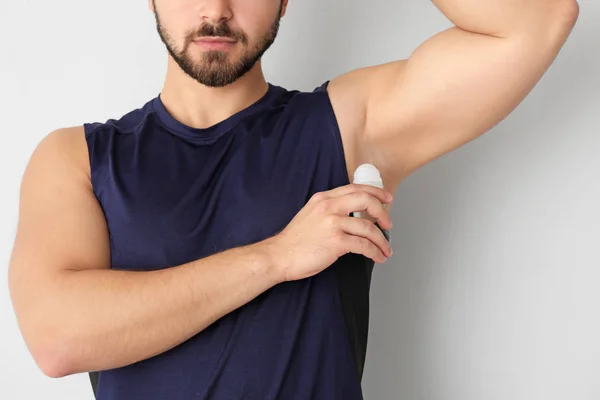 Csinos, fiatal férfi dezodor használata a világos háttér — Stock Fotó