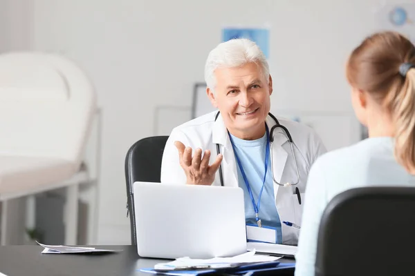 Mature male doctor working with patient in clinic — Stok fotoğraf