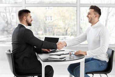 Banka müdürü ve adam ofiste el sıkışıyor.