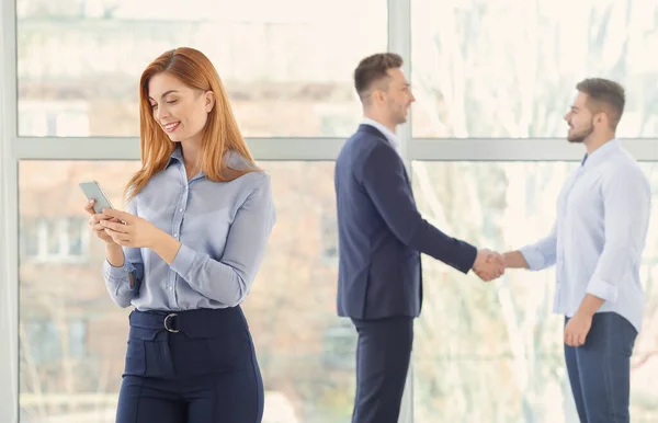 Portrait of young bank manager with mobile phone in office