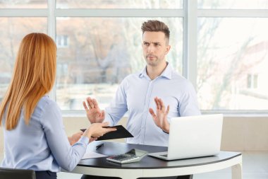 Bank manager working with displeased man in office