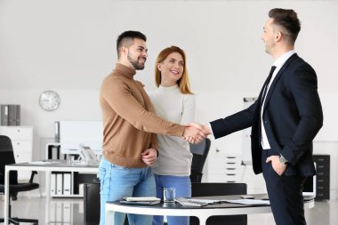 Bank manager and clients shaking hands in office clipart