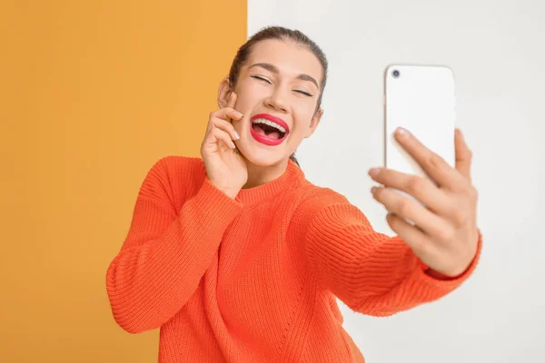 Hermosa mujer joven tomando selfie sobre fondo de color — Foto de Stock