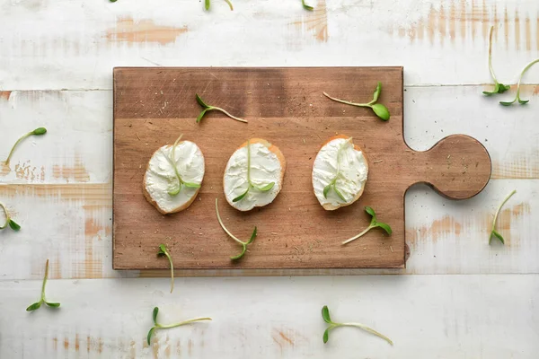 Slices of tasty bread with cream cheese on white wooden background — Stock Photo, Image