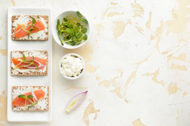 Sandwiches with tasty cream cheese and salmon on white background