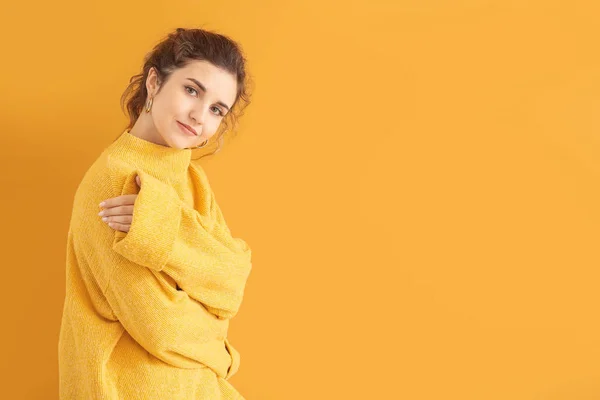 Beautiful young woman in warm sweater on color background — Stock Photo, Image