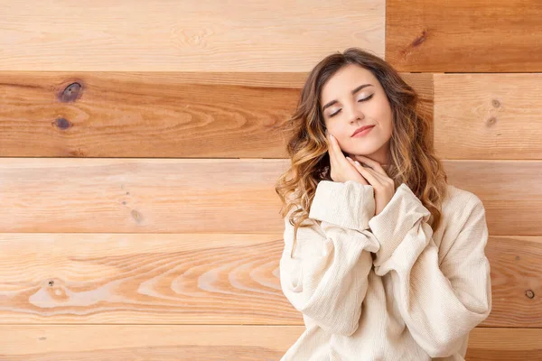 Beautiful young woman in warm sweater on wooden background — Stock Photo, Image
